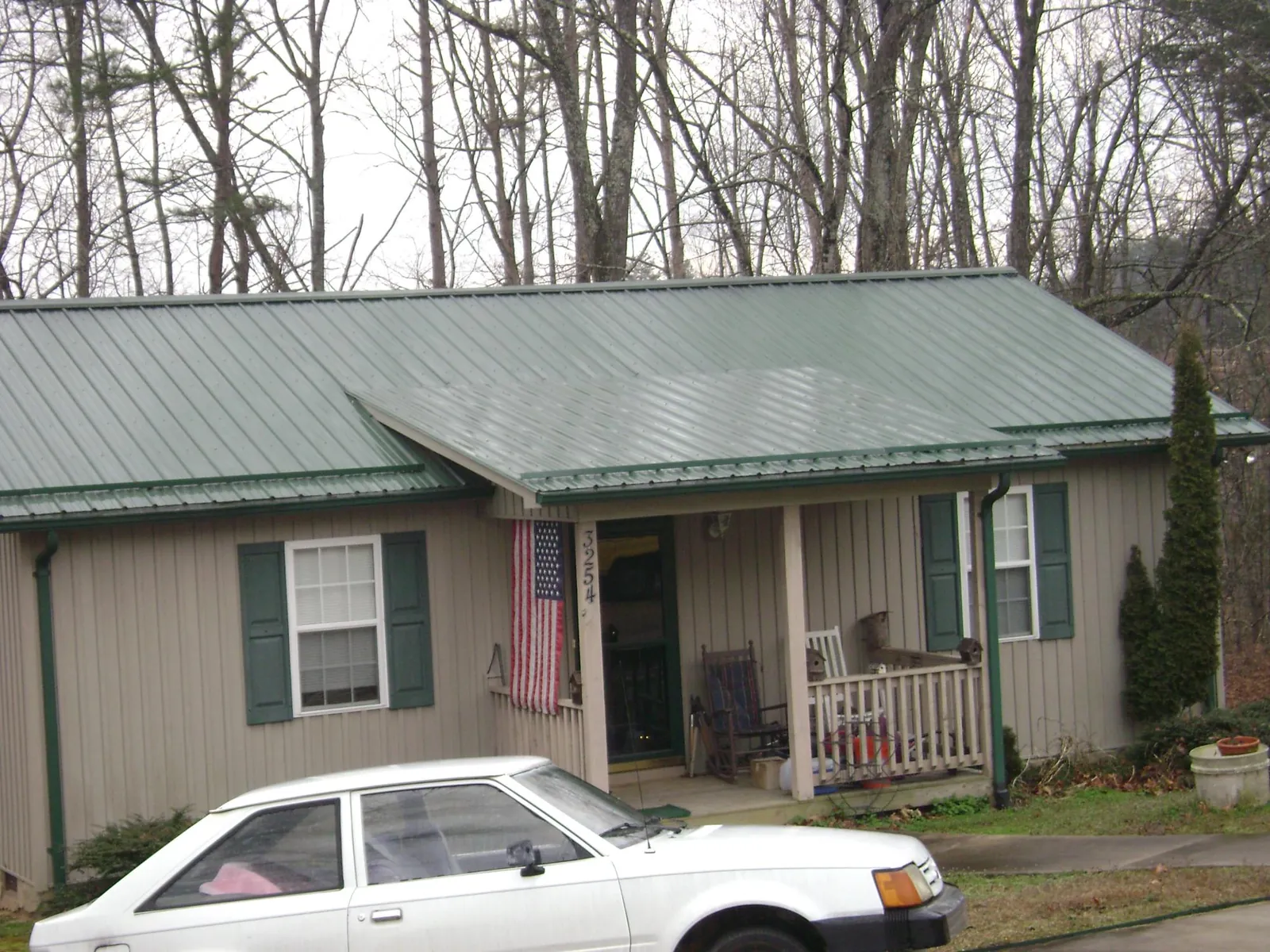 Green metal roof and front porch on a tan sided cottage in Worthington